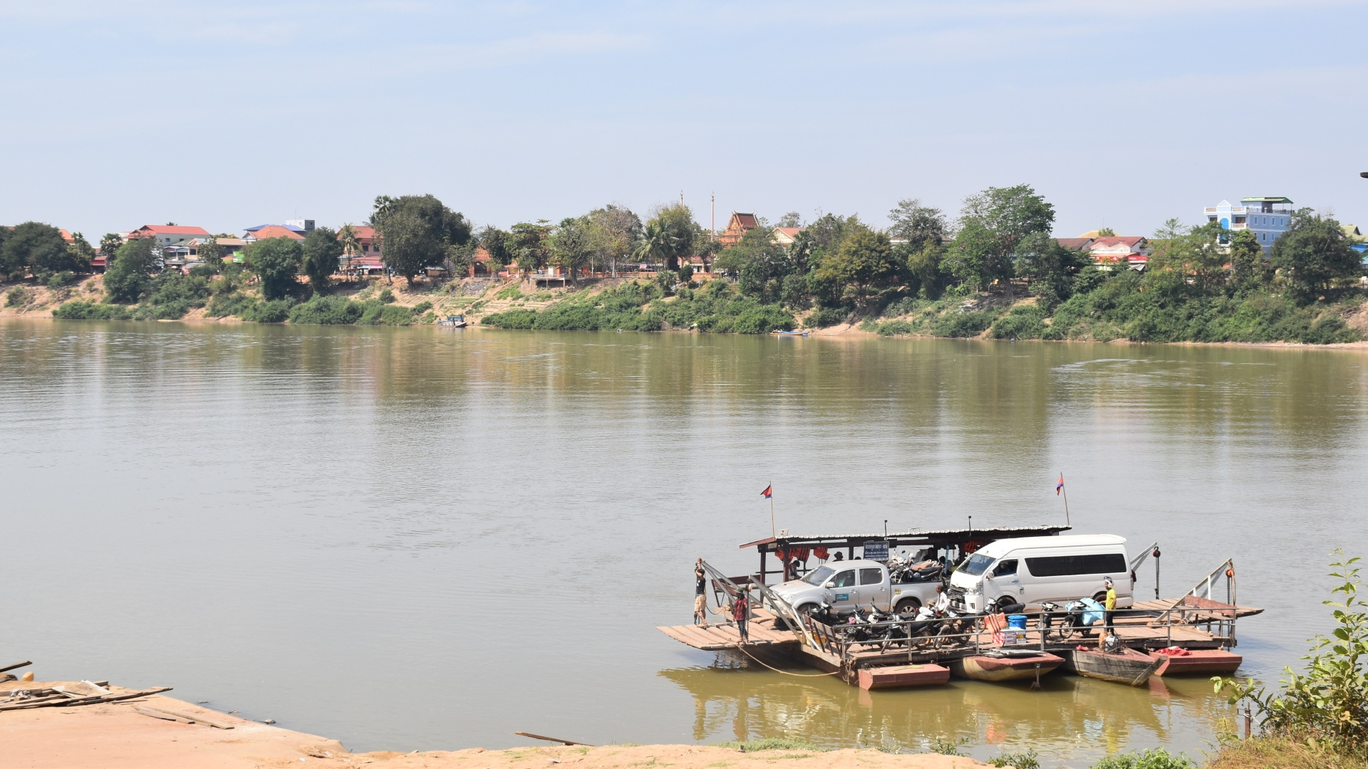 ehicles and participants being transported across the river on a small ferry boat in Stung Treng Province, illustrating the challenging travel conditions required to reach remote malaria-affected areas during field visits.