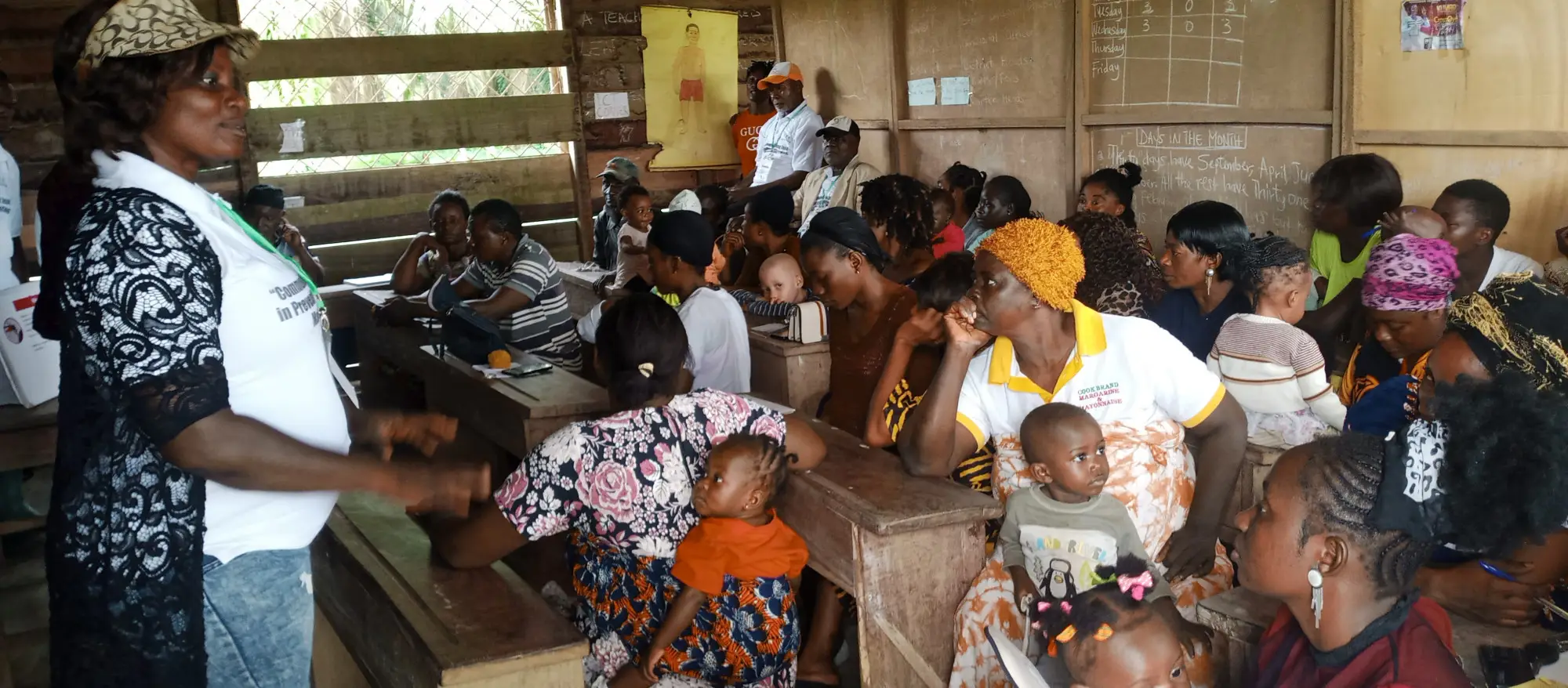A community worker talks to a class of mothers with their children