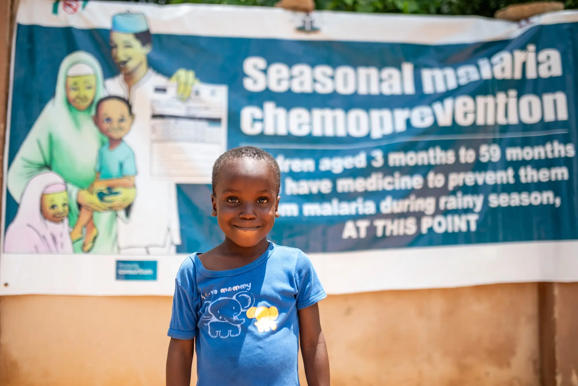 A child stands in front of a poster for SMC in Jigawa state, Nigeria in 2023