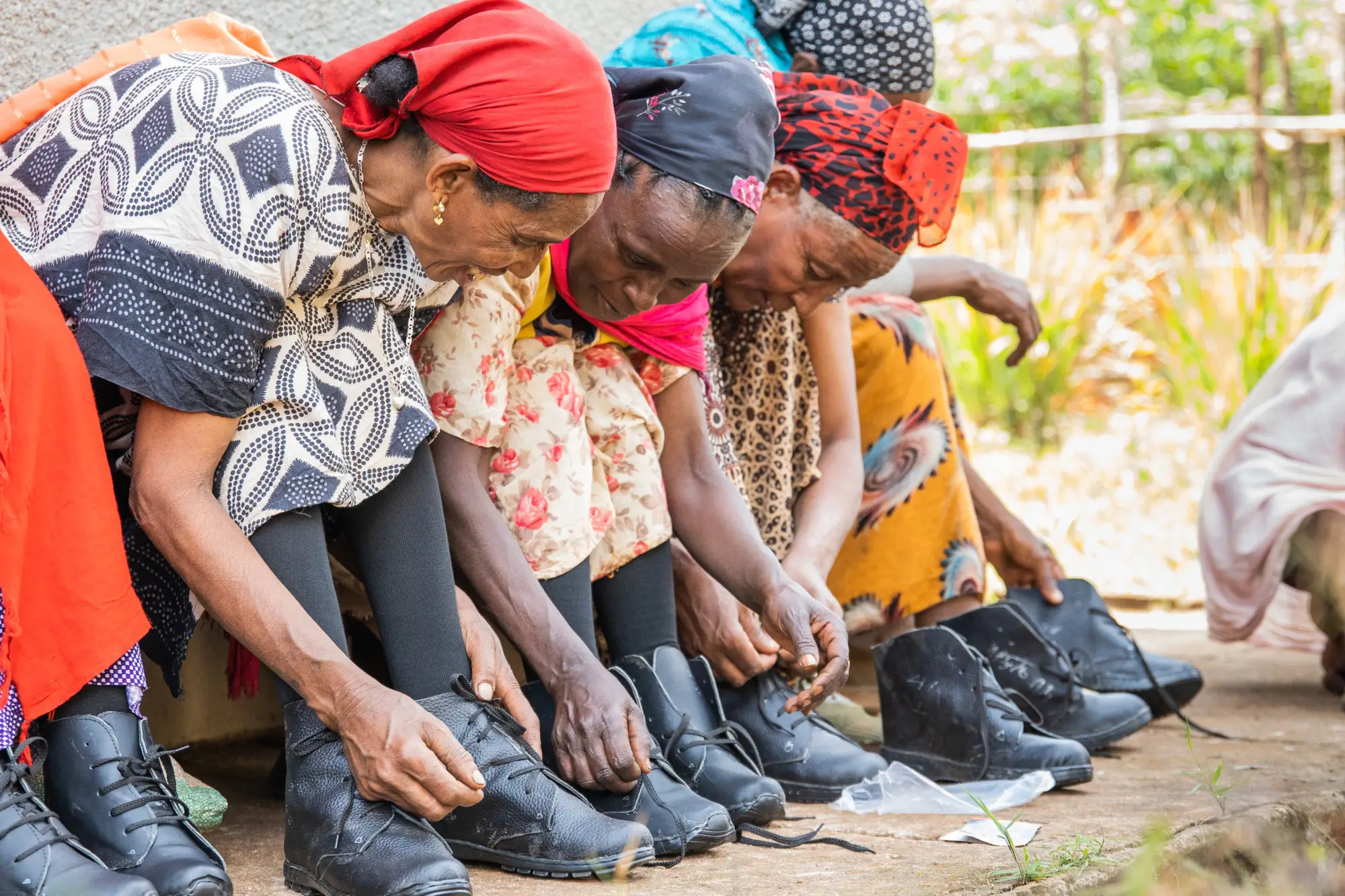 Women lace up new pairs of shoes, as part of the Happy Feet project