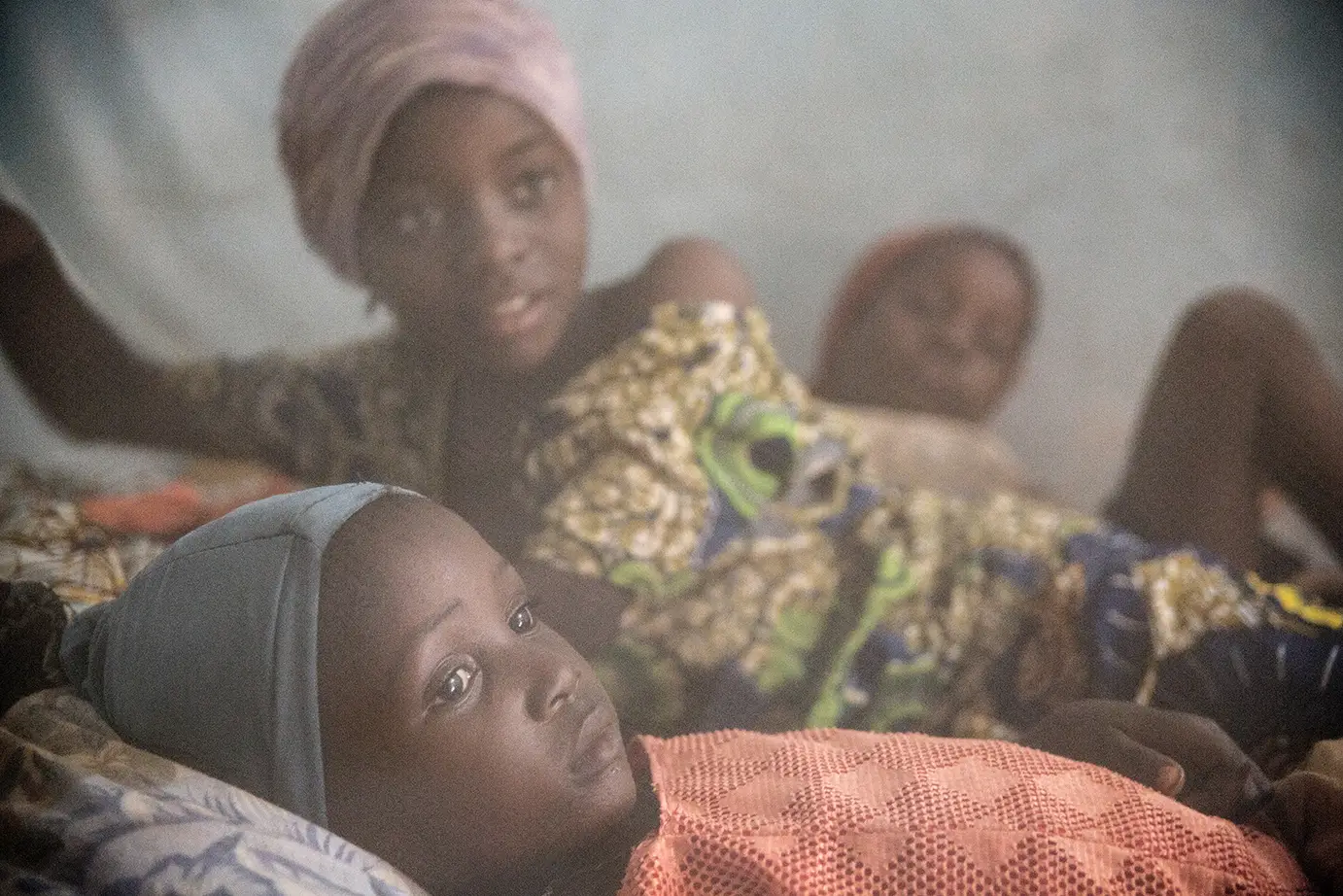 Two children sitting behind a bed net