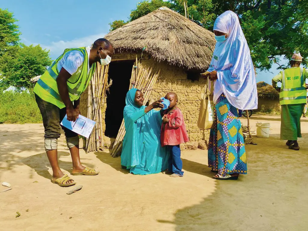 A woman gives a child SMC medication in Nigeria, 2021