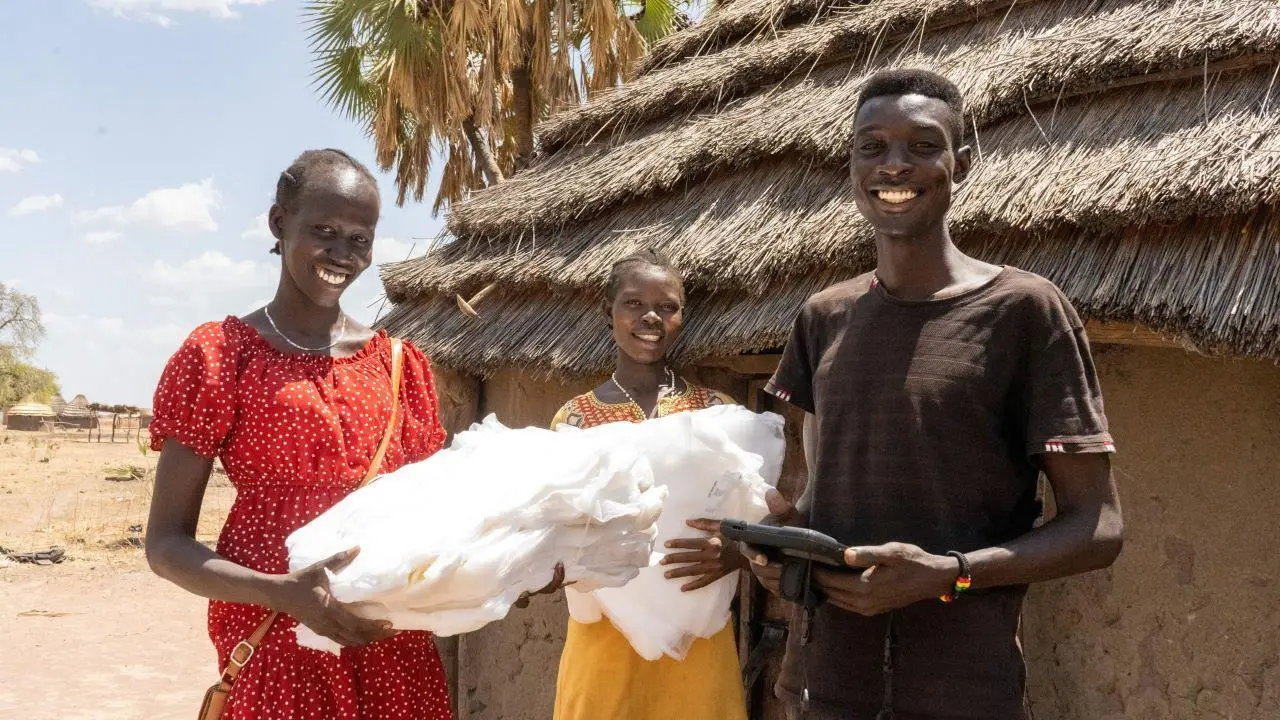 Athou Athou receives her net from Malaria Consortium registrars in Mayom Akoon village, Aweil West, South Sudan