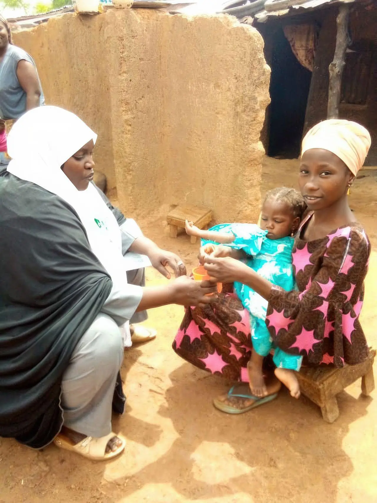 Child receiving SMC medication from a caregiver, under the direct supervision of a community distributor, Nigeria