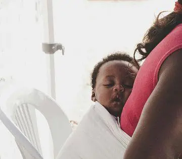 A child sleeps on a woman's back