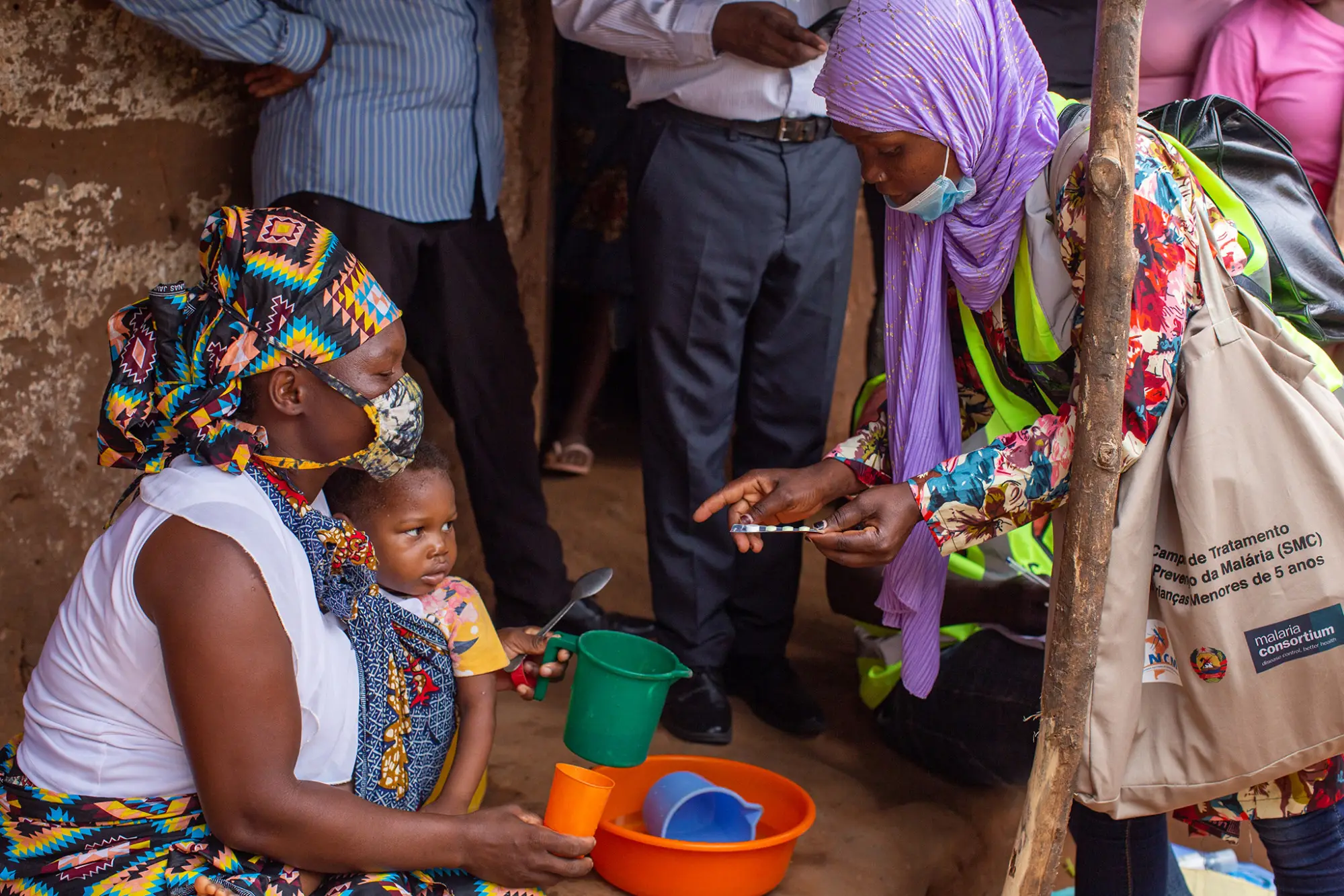 An SMC distributor showing a caregiver how to administer SPAQ medication to their child, Mozambique