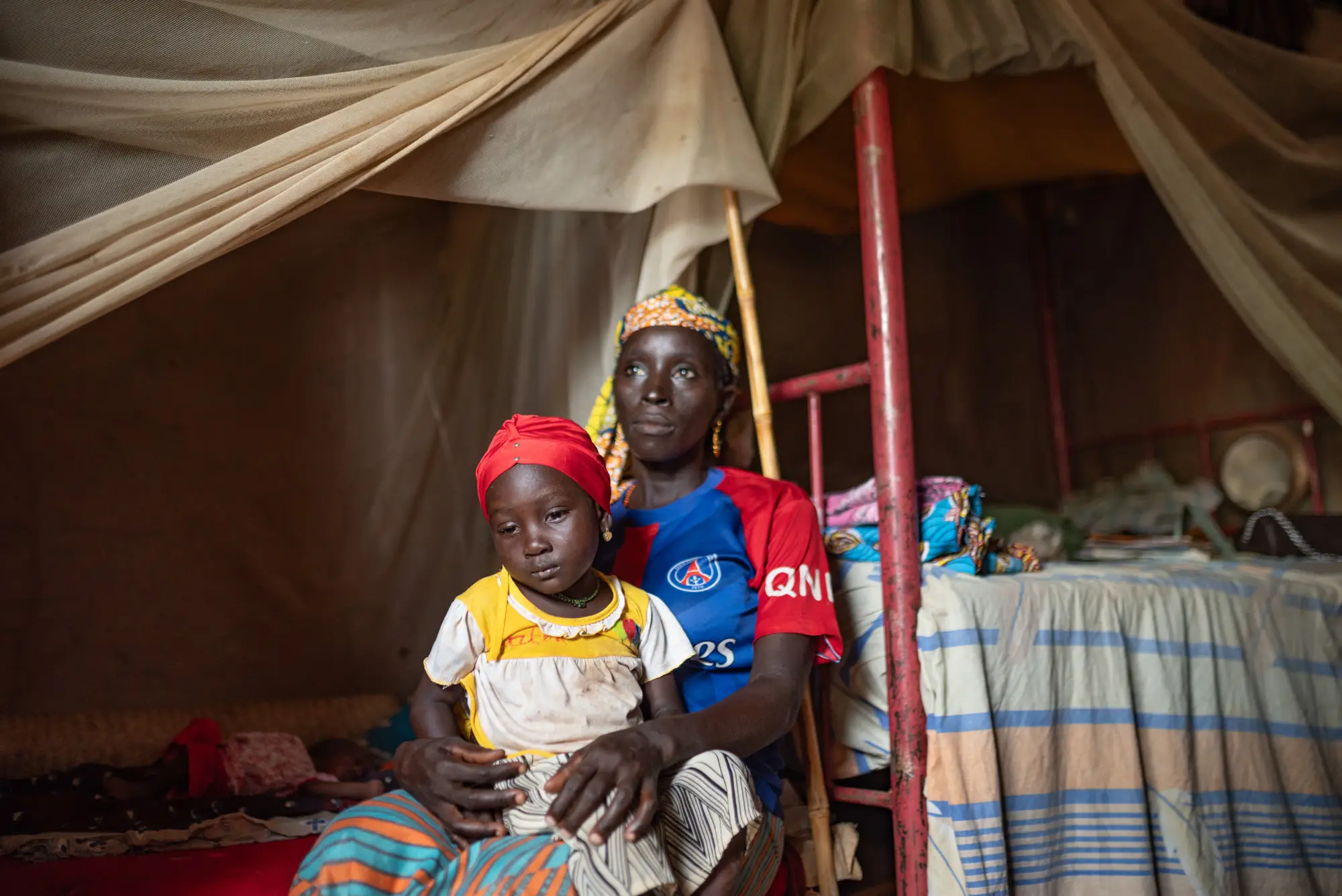 A child sitting on an adult's lap in Jigawa, Nigeria