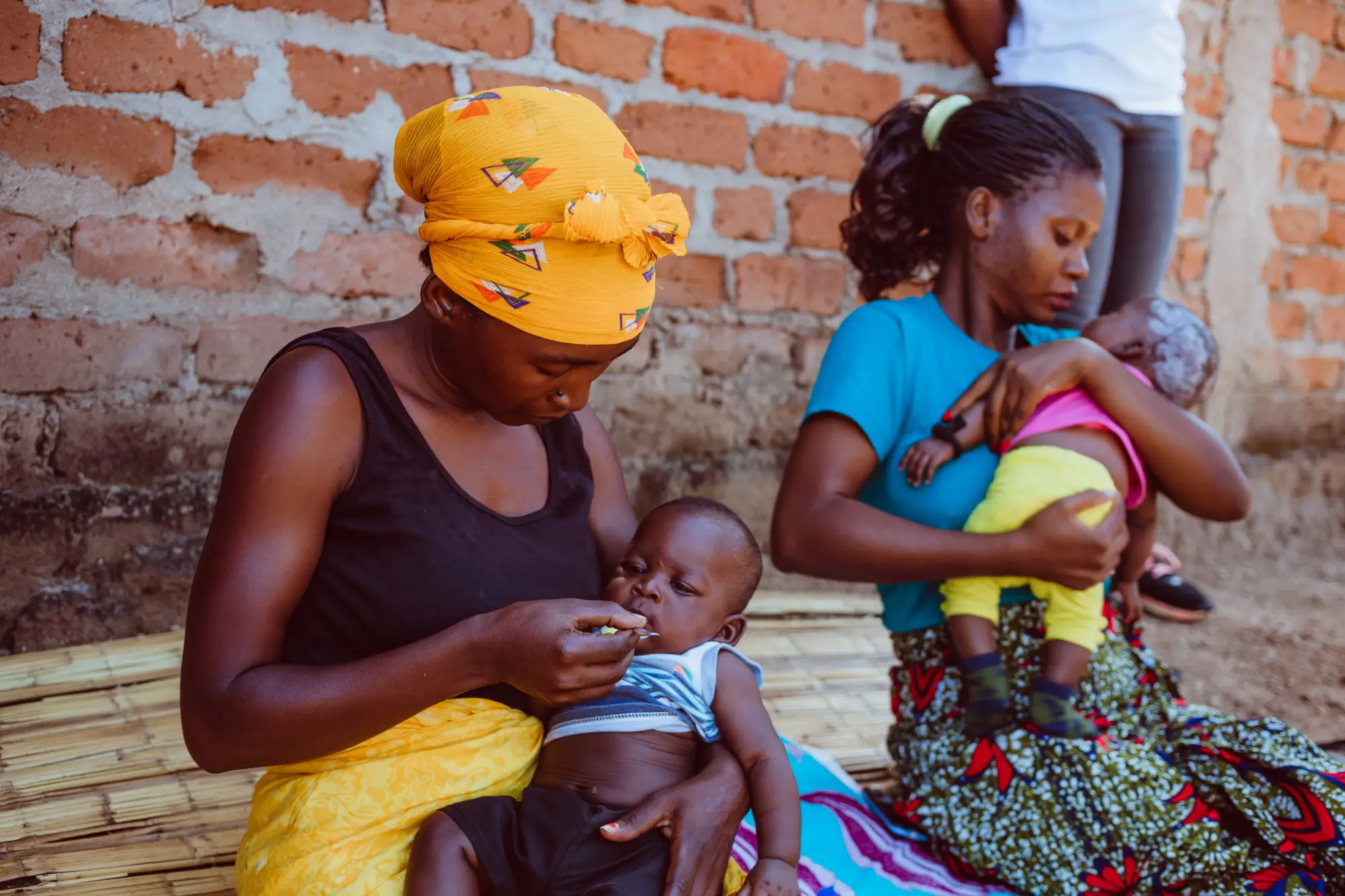 A woman gives medication to a child in Malema, Mozambique in 2022