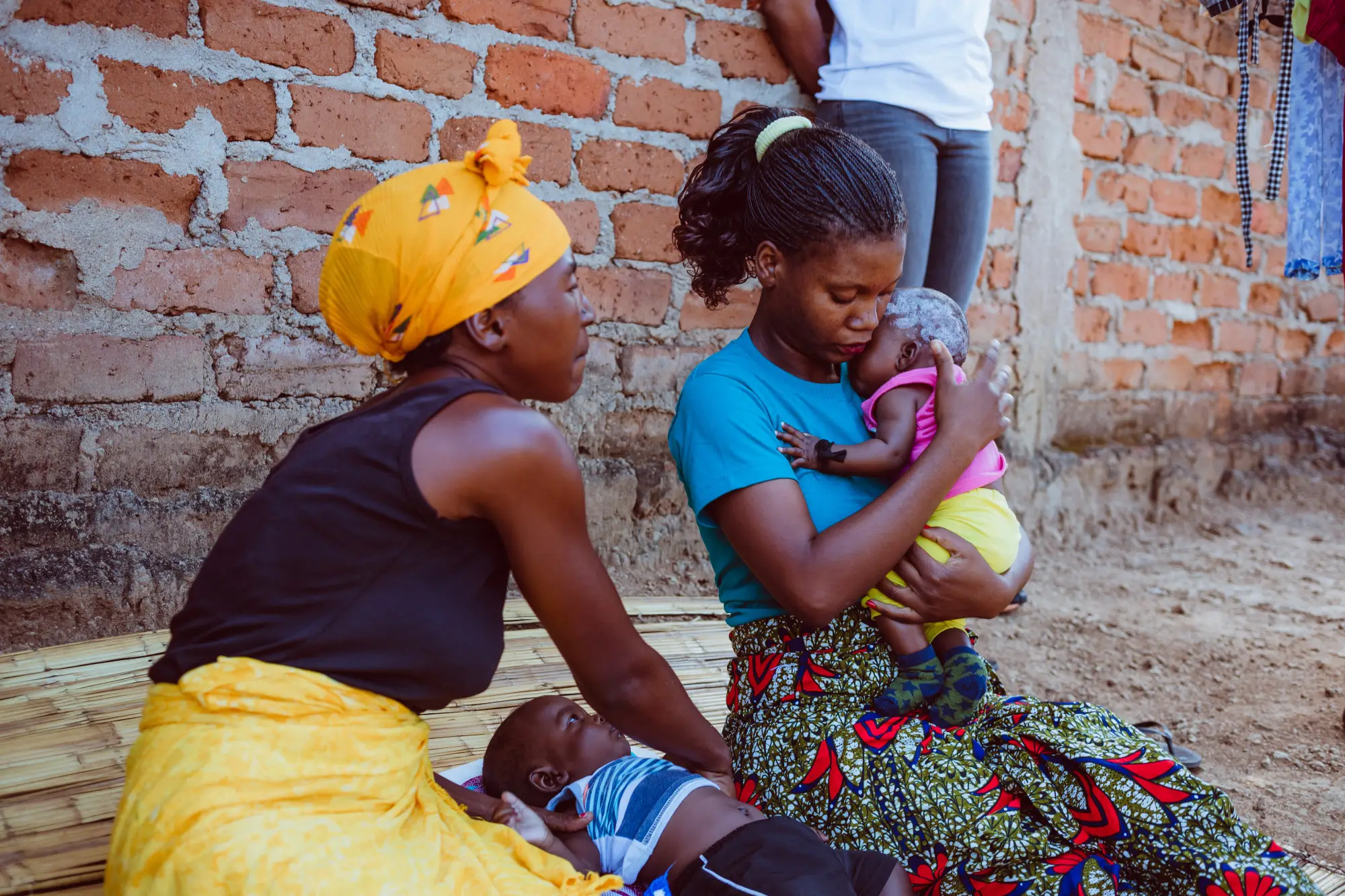 Two women sitting with their children in Malema, Mozambique