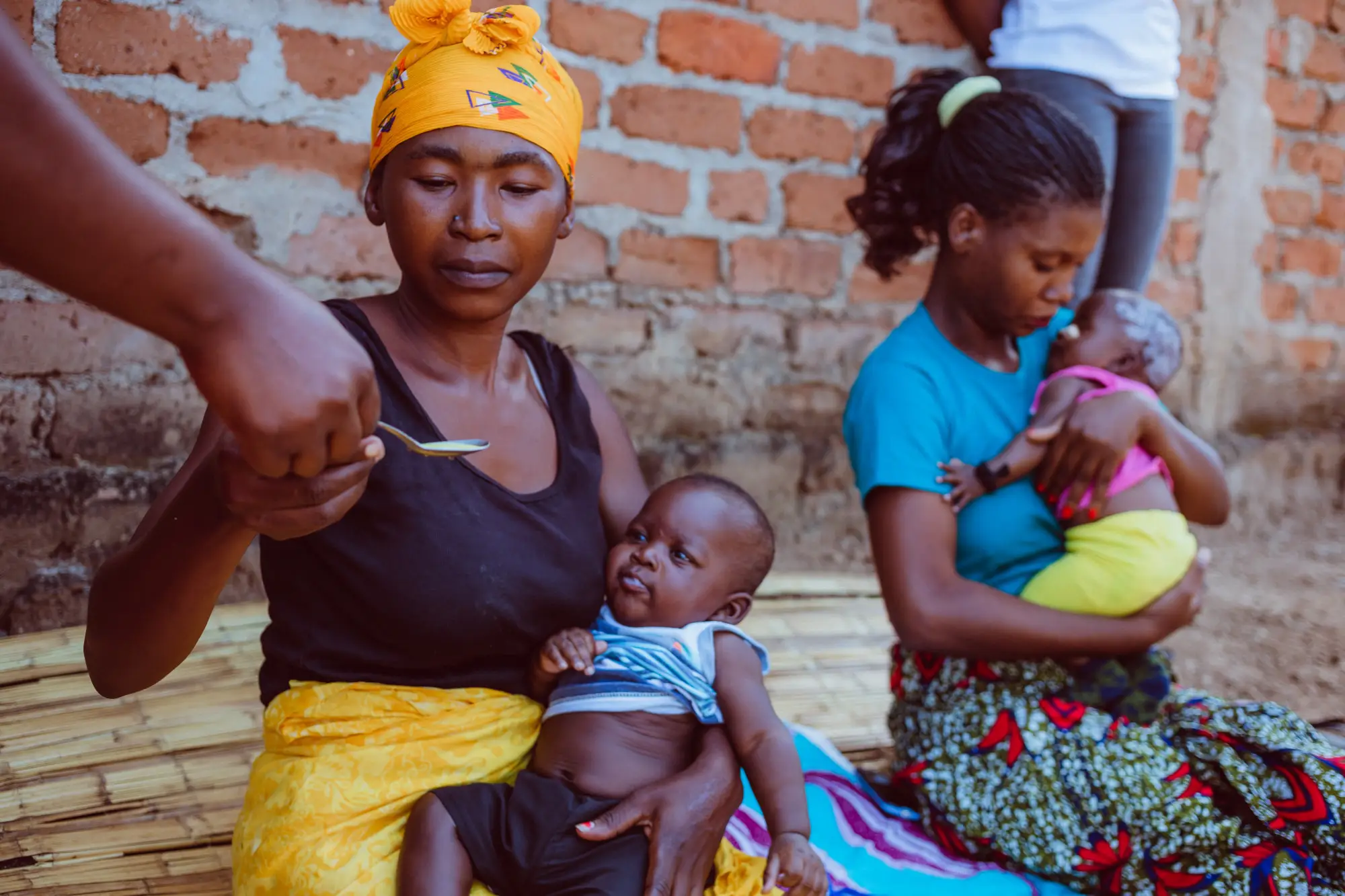 A woman feeds medication to her child in Malema, Mozambique in 2022