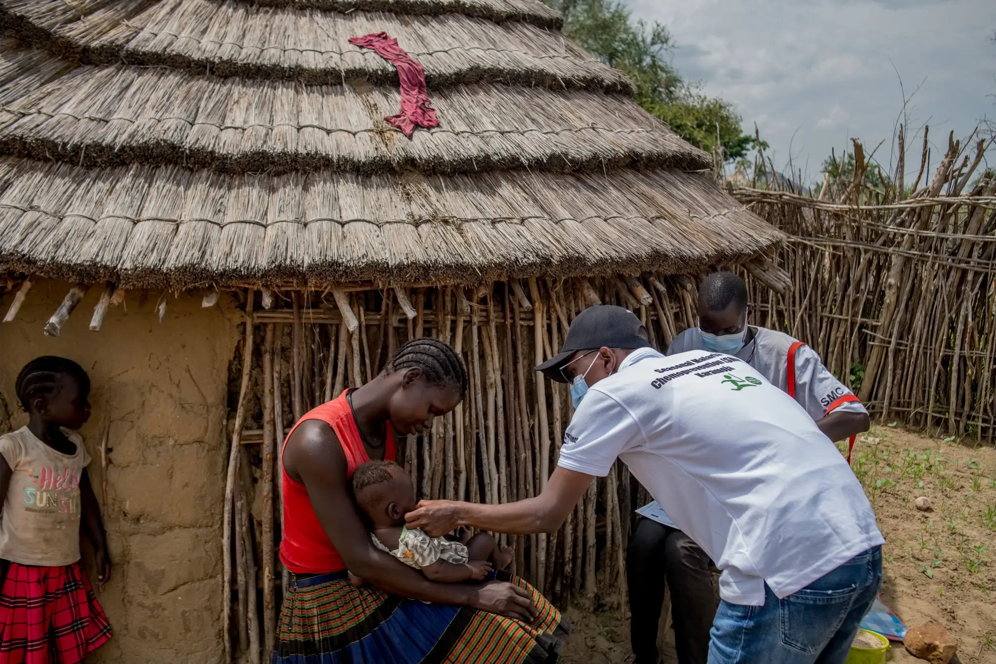 Health worker talks to mother and child while delivering SMC medications to nomadic community, Karamoja, Uganda.