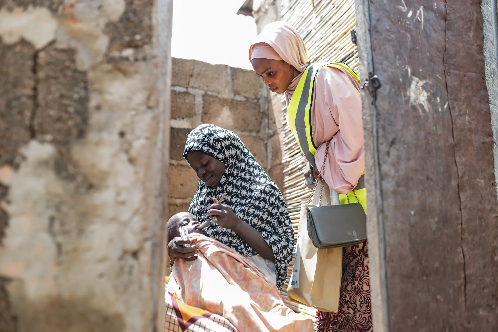 Caregiver administers SMC medicine to their child under the supervision of a health worker, Kano state, Nigeria