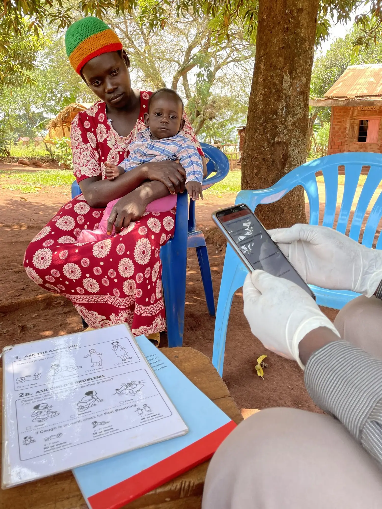 Mother and child taking part in questionnaire where the data is recorded on the project app, Buikwe, Uganda