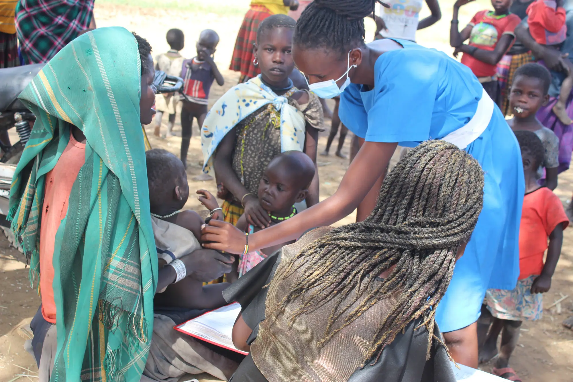 Community health worker treats small child during a community outreach session in Karamoja, Uganda