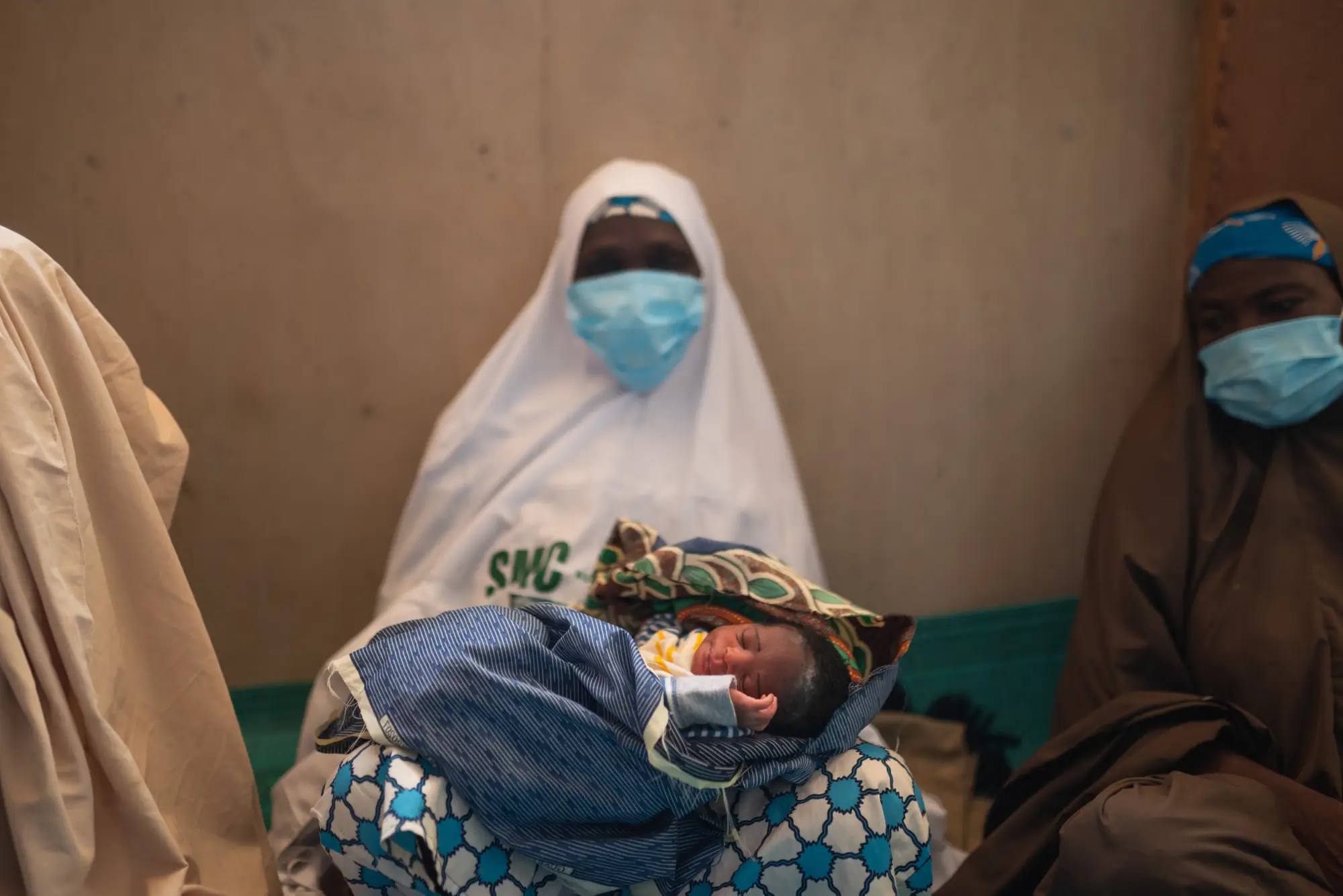 A masked woman holds a baby.