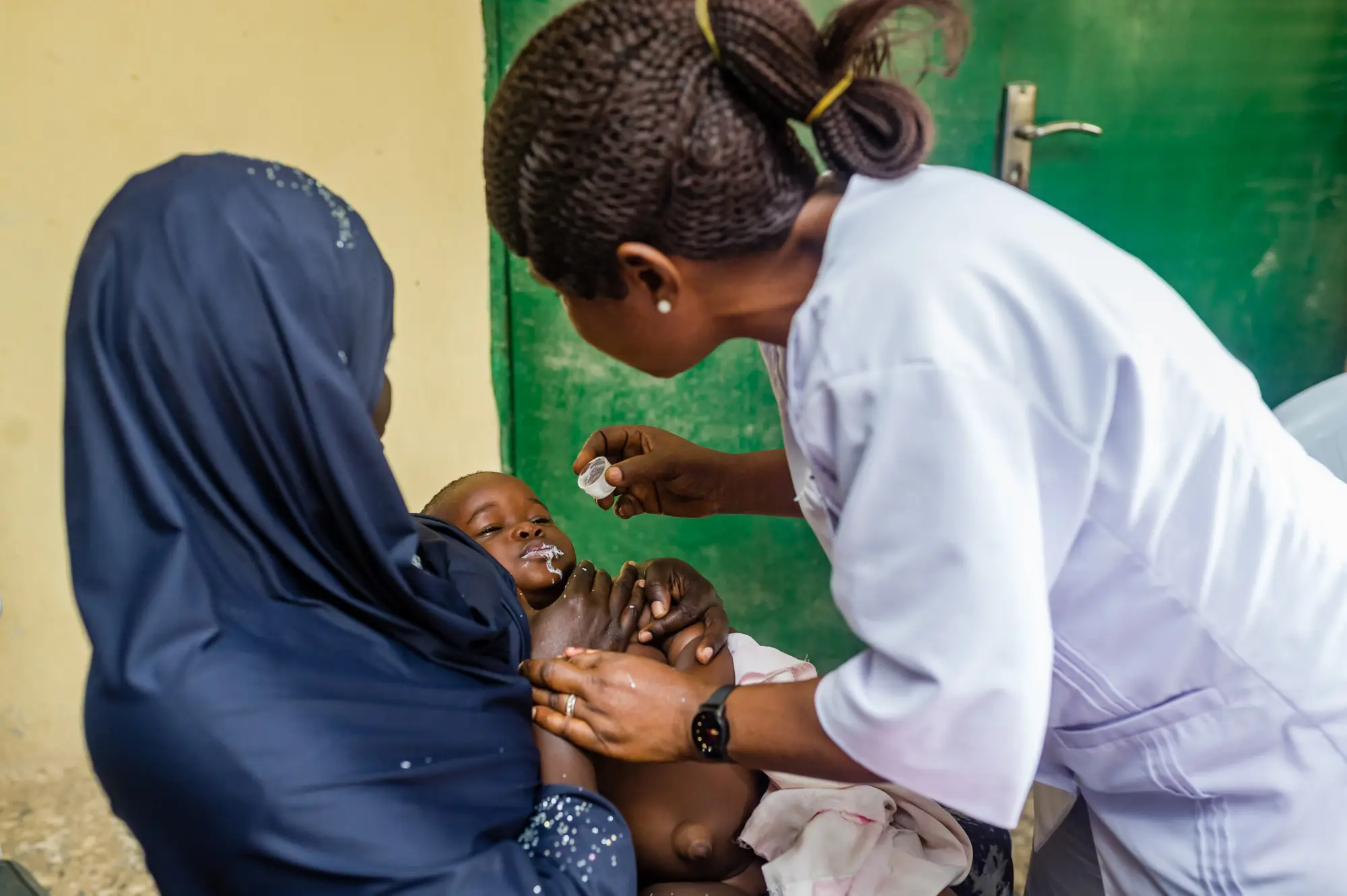 A community health worker feeds a child medication