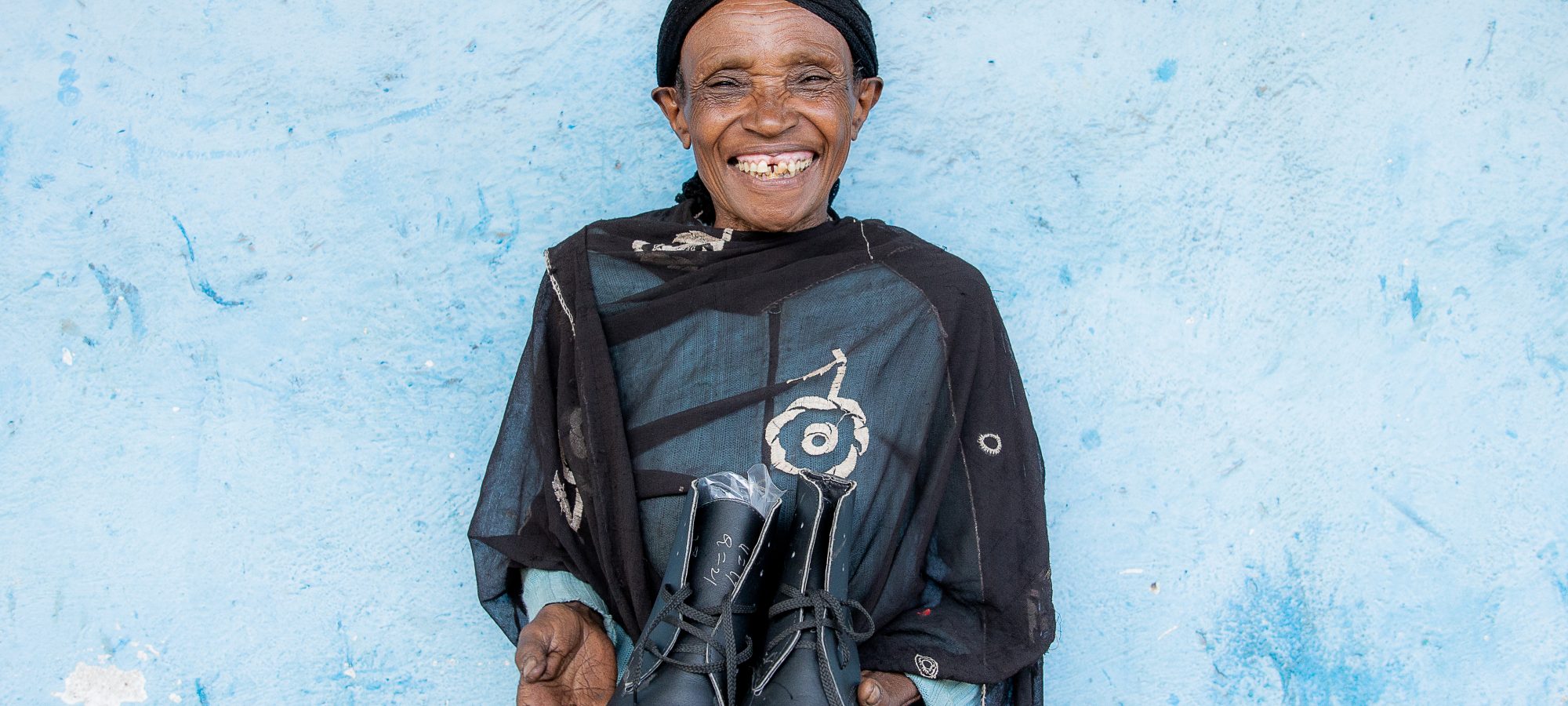 Photo shows Ethiopian woman holding new boots - photo by Genaye Eshetu