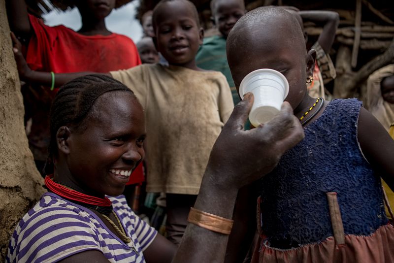 A mother is helping her daughter to drink the antimalarial medicine dissolved with water into a cup