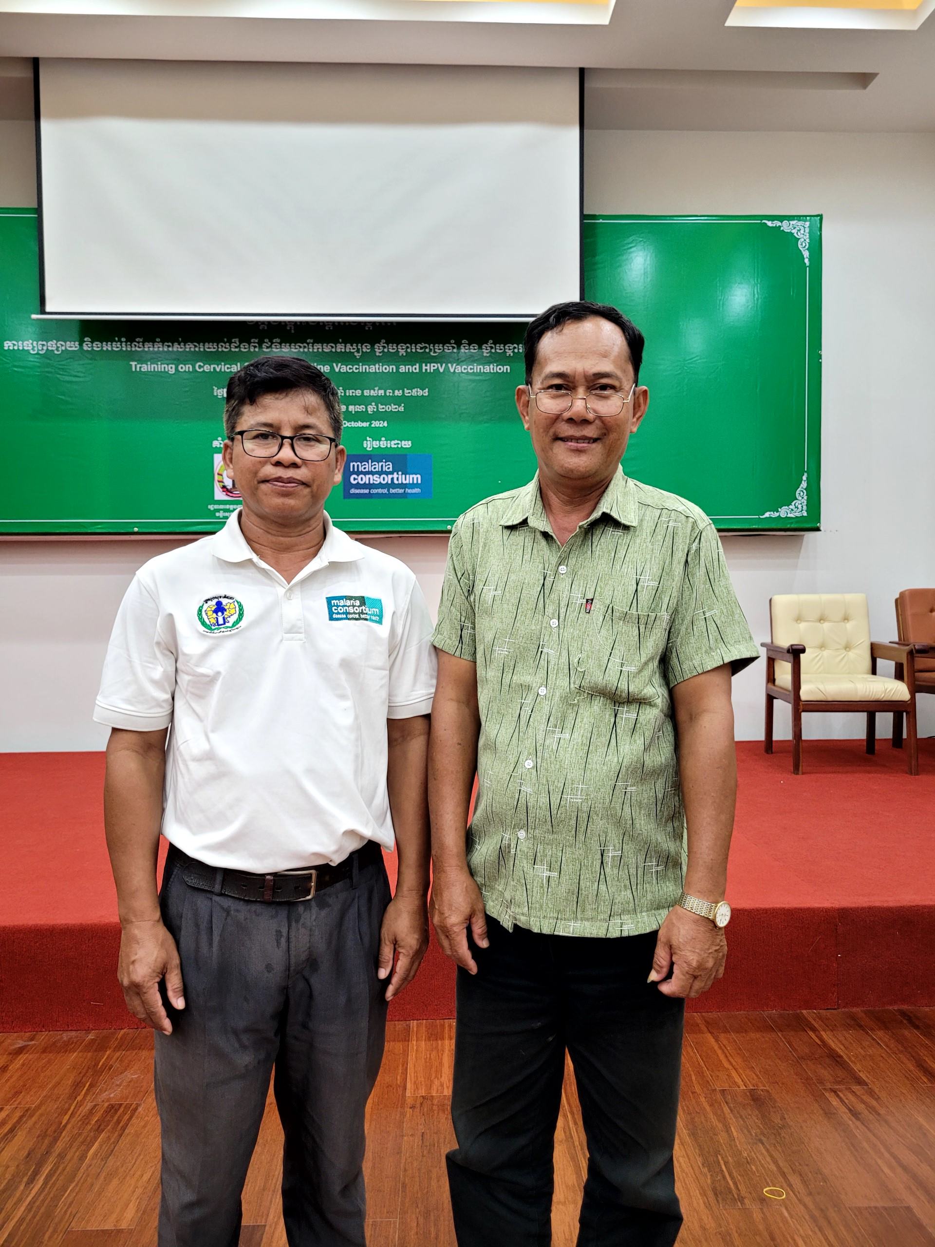 Village health volunteer standing with a Malaria Consortium employee