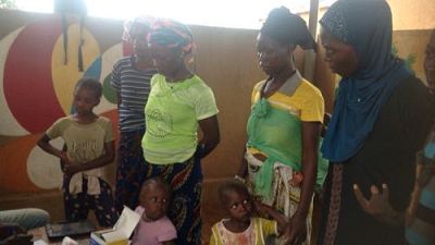 Mothers wait with their children to receive their first dose of SMC