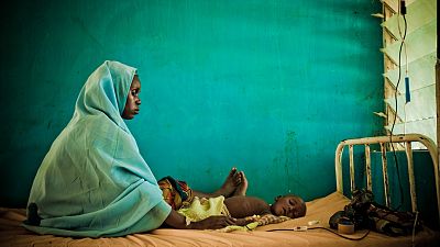 In northern Nigeria, a child is treated for malaria and his mother waits by his side. The classic symptoms of malaria consist of bouts of fever, chills, sweats, headaches, muscle aches, nausea and vomiting. Once contracted, it can mean death in just a few days for a young child. Malaria, a largely preventable disease transmitted by infected mosquitoes, kills hundreds of thousands each year. Most deaths occur among children living in Africa where a child dies every minute from malaria. In Nigeria alone, WHO estimated that over a quarter of a million people died from malaria in 2012.