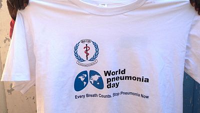 Pneumonia Diagnostics Research Assistant, Gabriel Garang holding up the a t-shirt for World Pneumonia Day.